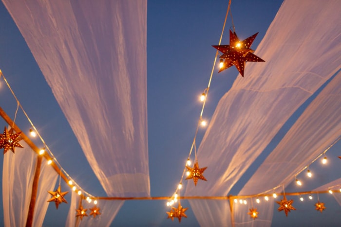 Des lanternes étoilées sont suspendues avec des guirlandes lumineuses dans le ciel du soir avec des draperies.