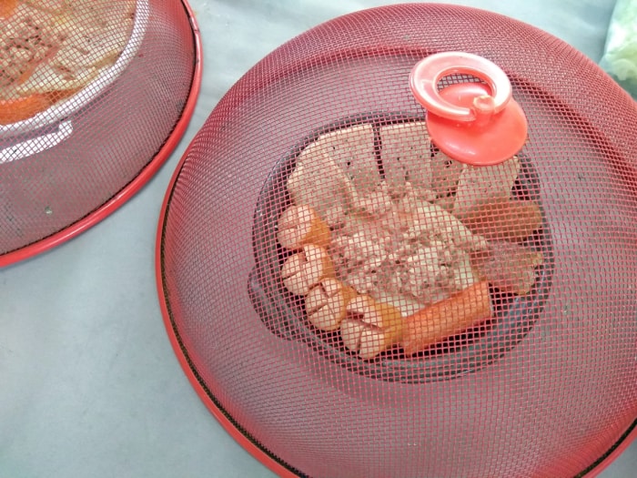 Des dômes en maille métallique rouge recouvrent les assiettes de nourriture à l'extérieur.