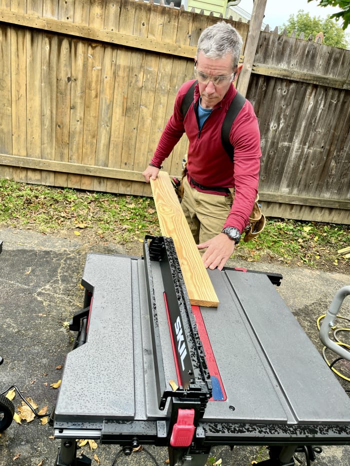 Le testeur de BobVila.com, Mark Clement, déchire une planche sur une scie à table portable Skil.