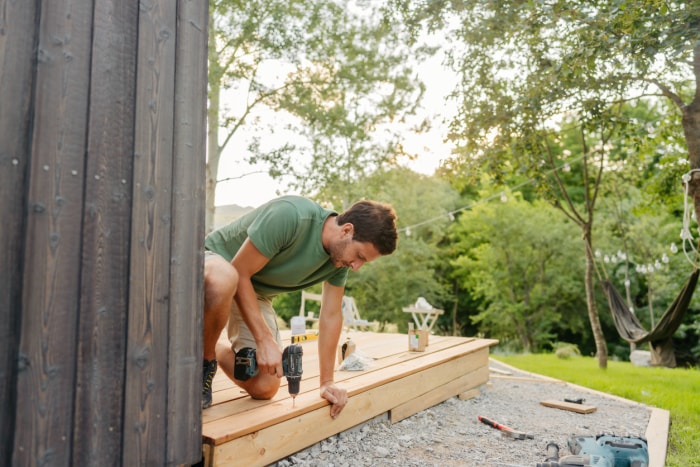 iStock-1429454751 déclaration de revenus améliorations domiciliaires homme construisant une terrasse dans l'arrière-cour