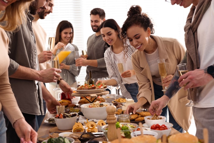 groupe-de-jeunes-tenant-des-coupes-de-champagne-et-se-servant-à-un-buffet-partluck