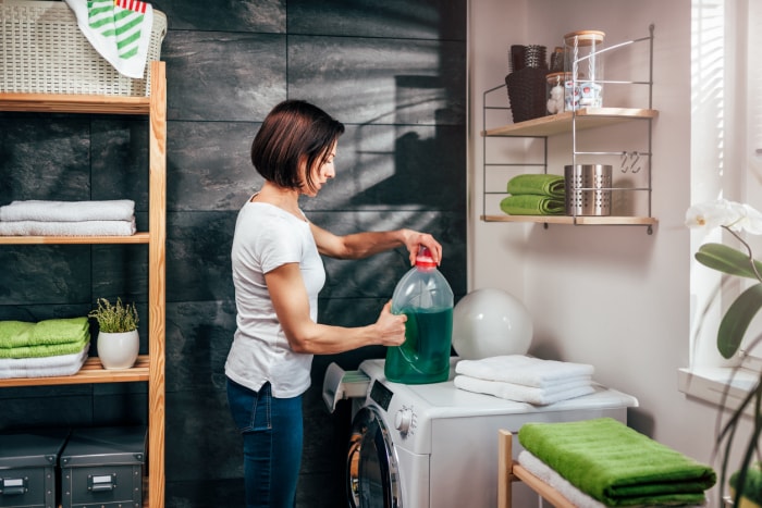 Femmes debout devant une machine à laver et ouvrant une bouteille de détergent liquide