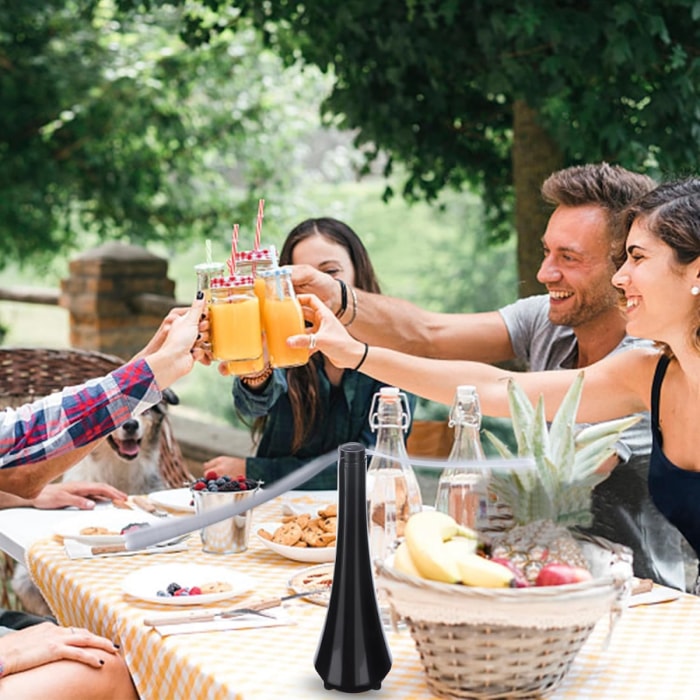 Groupe d'amis profitant d'un pique-nique en plein air avec un ventilateur sur la table.