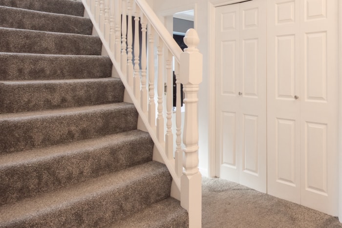 Un escalier en moquette de style cascade gris mène au couloir d'une maison.