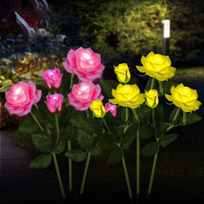 vue rapprochée des lumières de jardin en forme de roses roses et jaunes dans le jardin la nuit