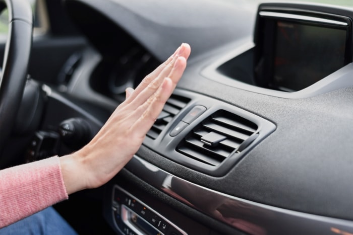 tâches d'entretien de la voiture - main devant le climatiseur de la voiture