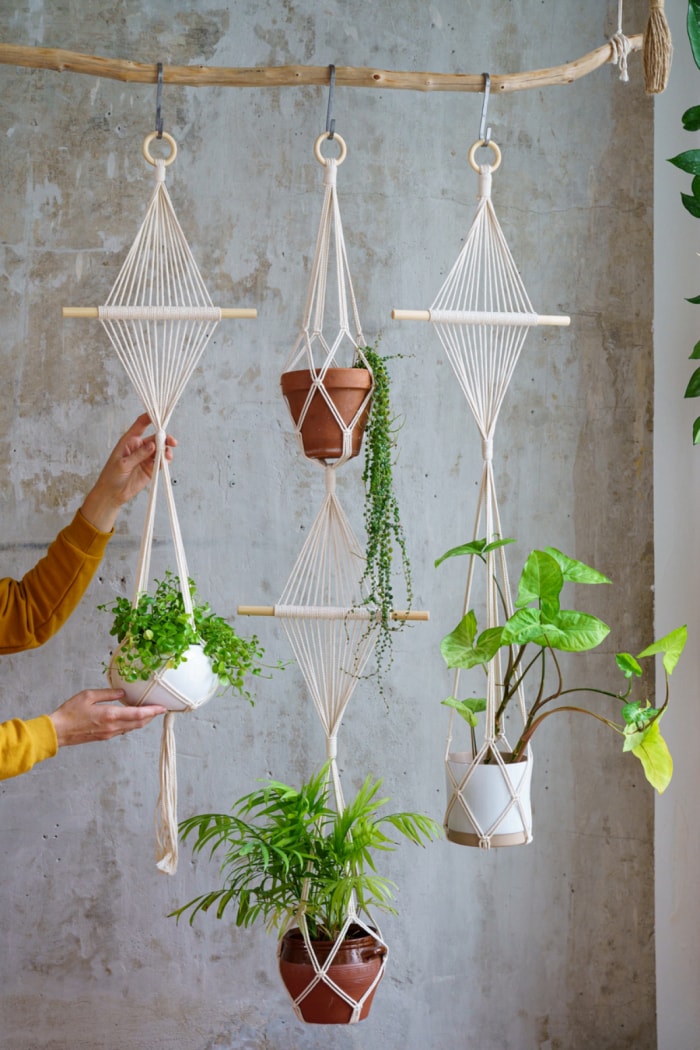 Personne tenant des pots de fleurs en macramé