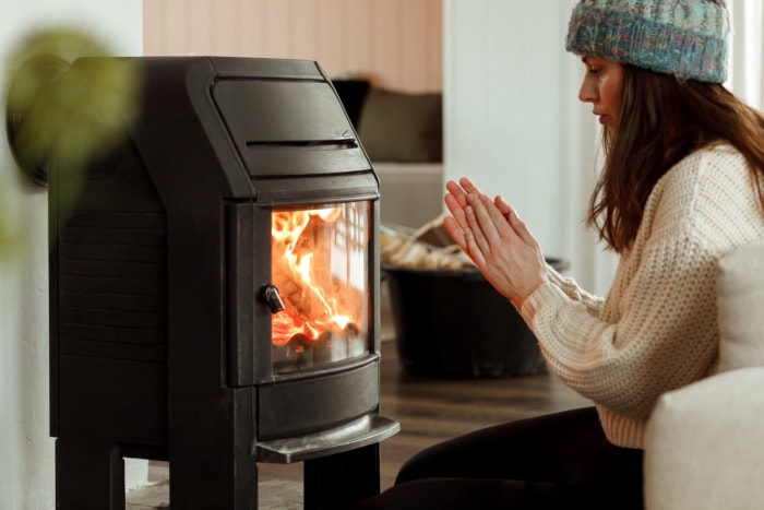 foyer à gaz ou électrique – une femme se réchauffant près du foyer