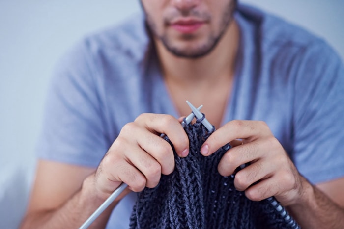 Une personne tricotant une couverture pour la maison.