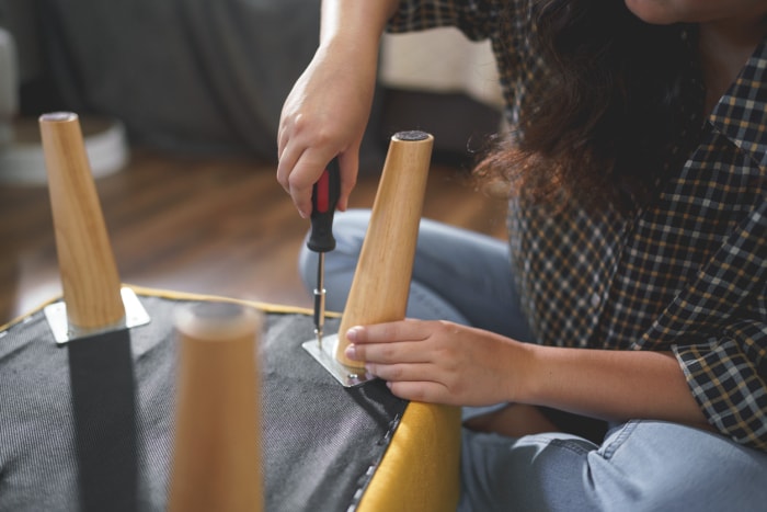 Les femmes serrent des vis avec un tournevis pour réparer les pieds d'une chaise et assembler des meubles.