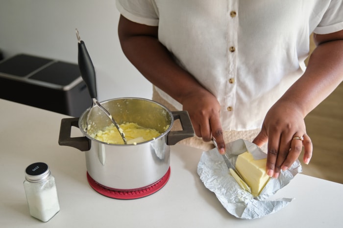 iStock-1436358615 manque de dinde en mettant du beurre dans la purée de pommes de terre