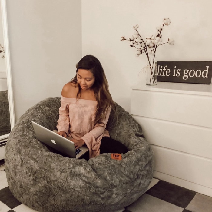 Femme avec un ordinateur portable sur un pouf Cordaroys