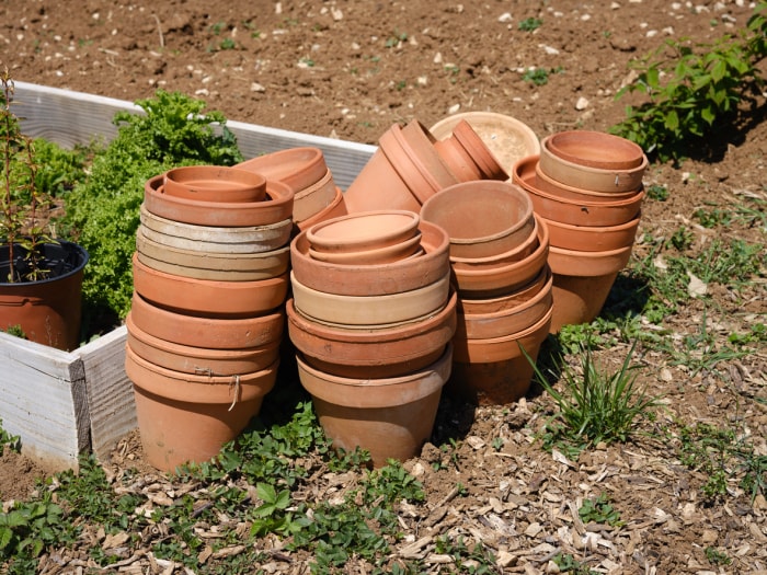 iStock-1314494255 14 astuces pour protéger votre jardin des intempéries pile de pots en terre cuite à côté du parterre de plantation