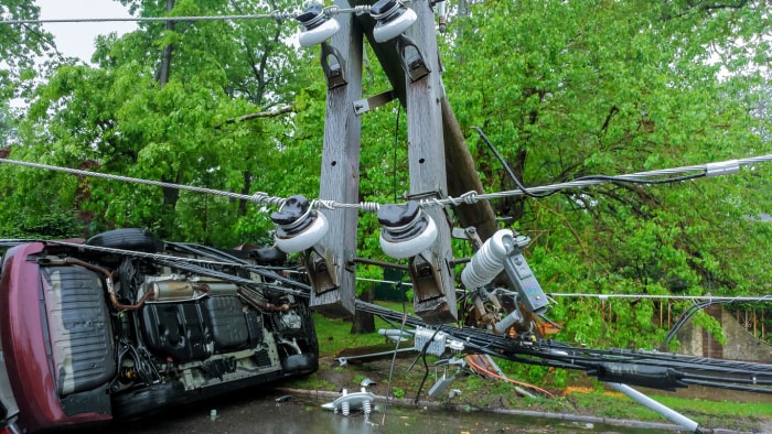 Une voiture endommagée et renversée heurte un poteau électrique tombé.