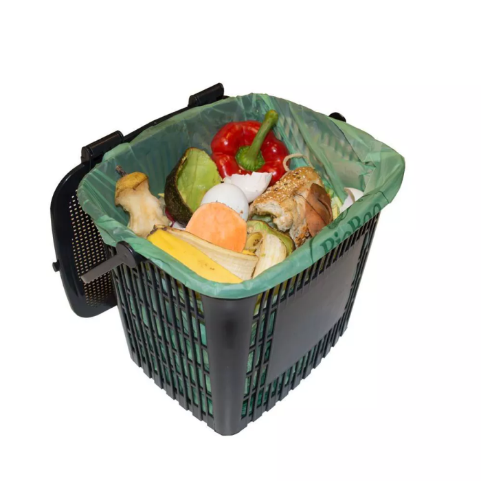 Un bac à compost contenant des restes de nourriture est doublé d’un sac compostable vert.