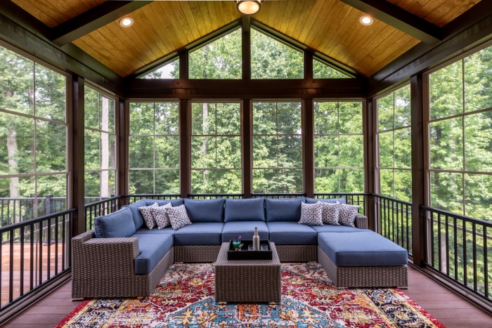 véranda fermée avec mobilier de jardin bleu et tapis persan avec murs et toit en verre offrant de l'ombre