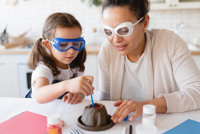 Jeune mère aidant sa fille à réaliser une expérience scientifique sur l'éruption d'un volcan dans sa cuisine. Laboratoire de chimie à la maison. Bicarbonate de soude pour un projet