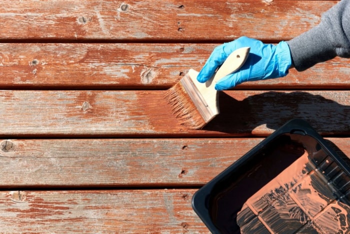 Quelqu'un portant des gants peint une terrasse en bois