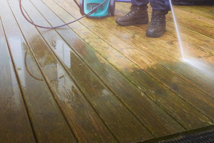 gros plan d'une personne nettoyant à haute pression une terrasse tachée