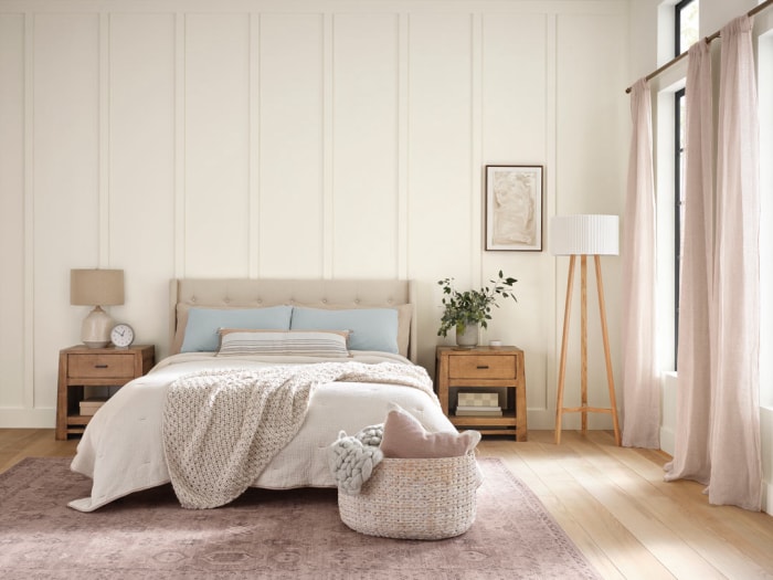 Chambre à coucher avec literie beige et planchers en bois clair avec murs peints en Alabaster de Sherwin-Williams.