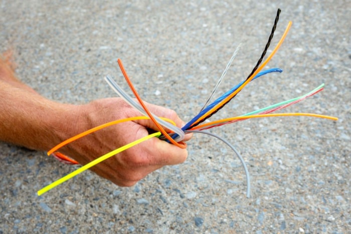 Person holding several of the best weed eater strings in hand