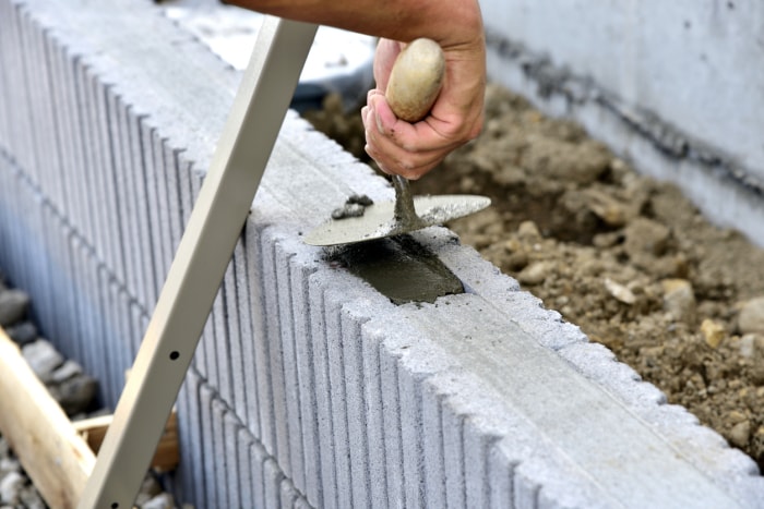 Travaux d'extérieur, construction d'un mur en blocs de béton : Remplir le mortier à l'aide d'une truelle à enduire