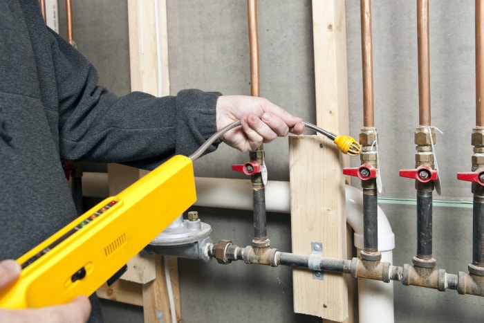 Un plombier vérifie les fuites de gaz à l'intérieur d'une vieille maison pendant la rénovation.