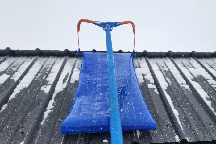 L'Avalanche ! Un râteau de toit est en cours de test pour retirer la neige légère d'un toit en métal.