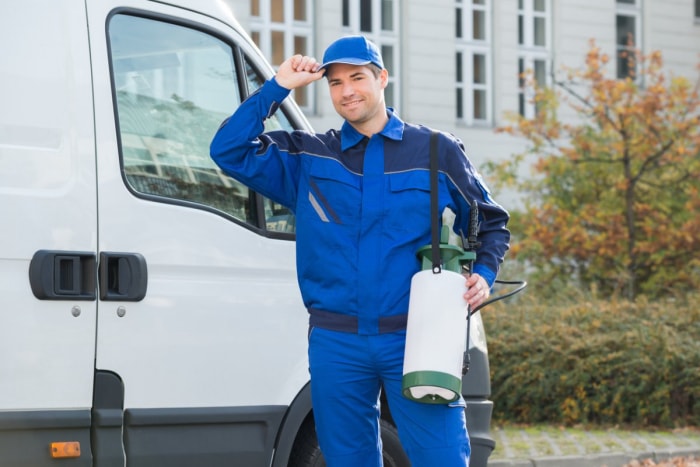 Un homme en costume de travail bleu tient un outil de lutte antiparasitaire.