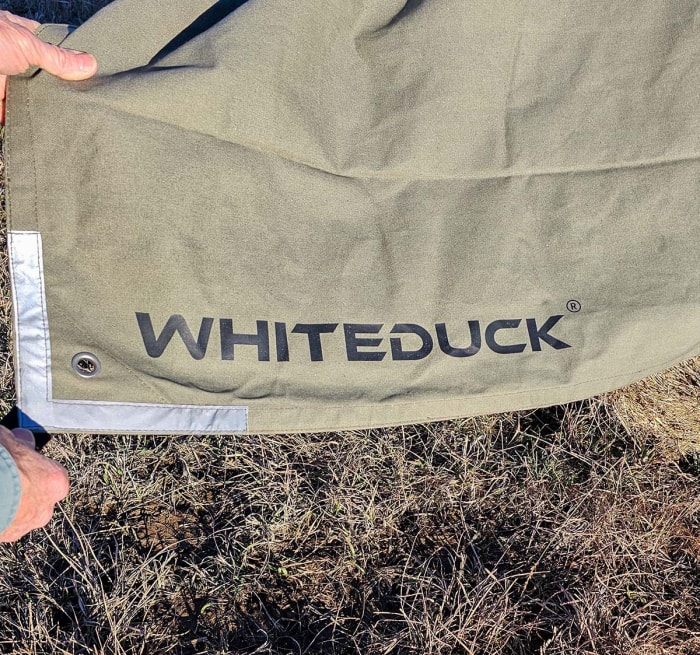 Une personne tient le coin de la bâche White Duck pour montrer l'œillet et le coin renforcés.