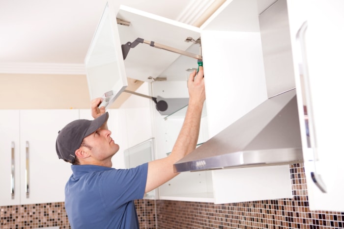 Homme installant une armoire murale supérieure