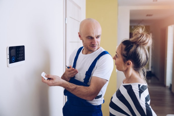 Un ouvrier montre à une femme comment utiliser un panneau de contrôle domotique. 