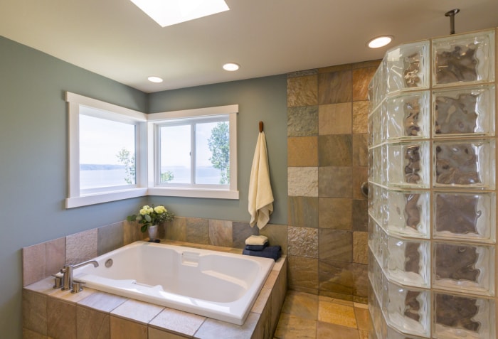 belle salle de bain moderne avec baignoire jacuzzi et un mur de fenêtres en blocs de verre