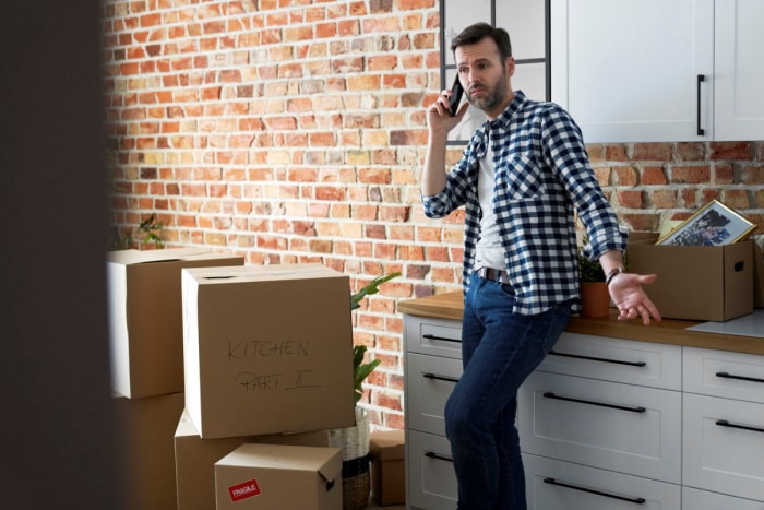 Un homme mécontent parle au téléphone au milieu de cartons de déménagement