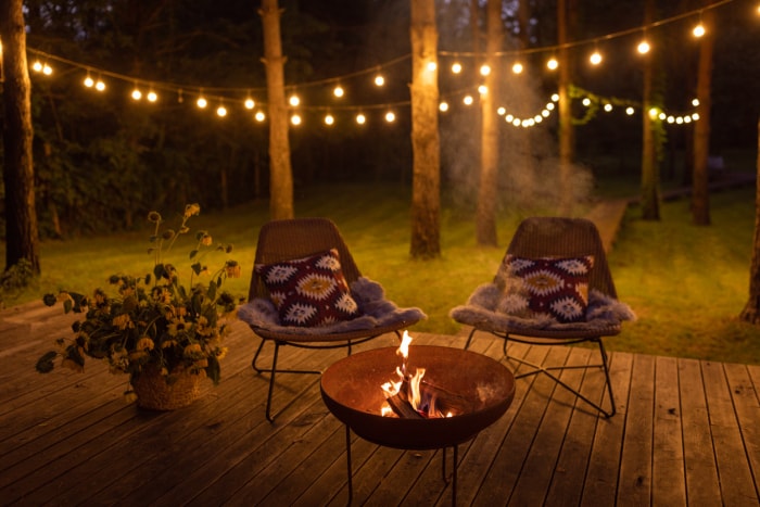 Véranda confortable aménagée avec foyer et chaises. Détails sur le thème de l'automne. Guirlandes lumineuses en arrière-plan.