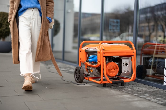 Générateur orange installé à l'extérieur d'un magasin alors qu'une femme passe dans la rue