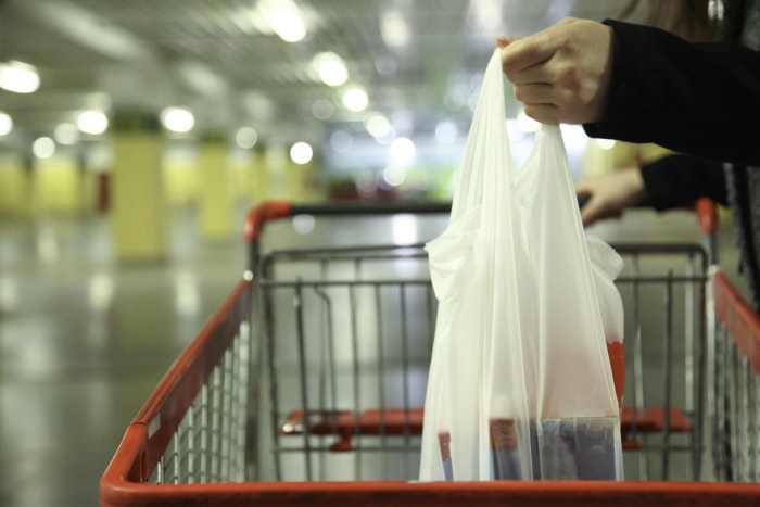 Un sac en plastique rempli de produits d'épicerie est placé dans un caddie.