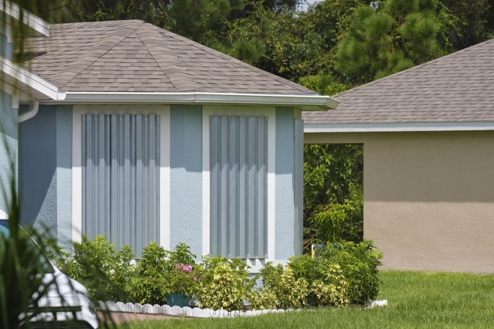 Une maison avec des volets anti-ouragan installés en prévision d'une catastrophe naturelle.