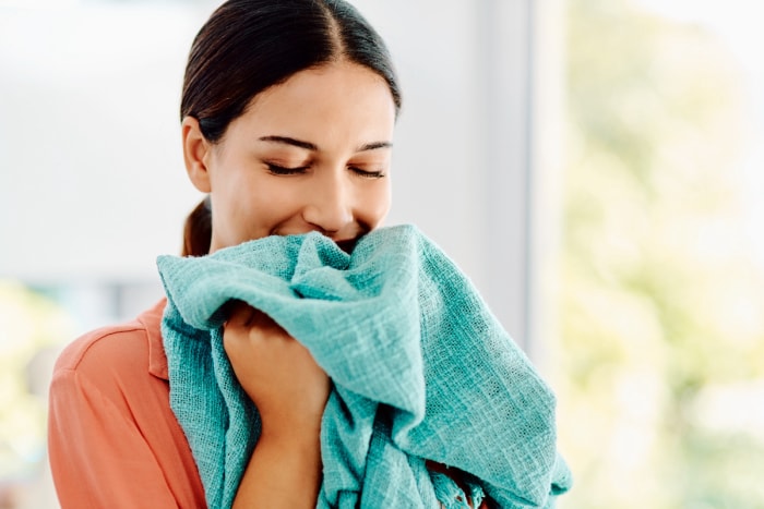 Femme sentant une serviette de couleur sarcelle fraîchement lavée