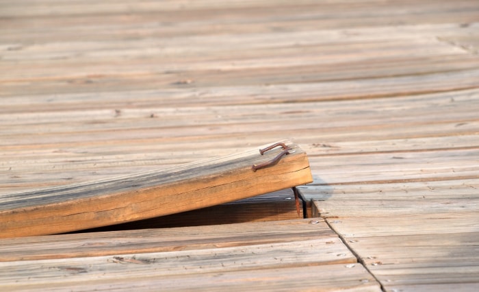 une-planche-de-bois-avec-des-clous-rouillés-dépasse-d'une-terrasse