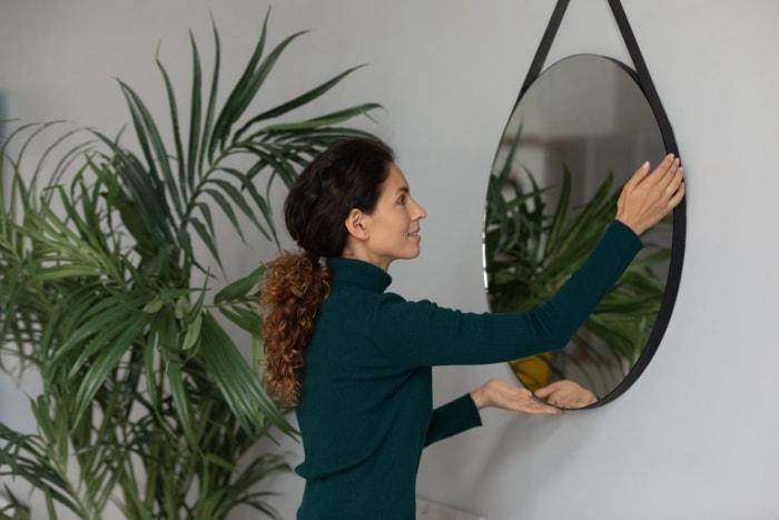 iStock-1297735499 Femme faisant des courses chez Home Depot en accrochant un miroir dans sa maison