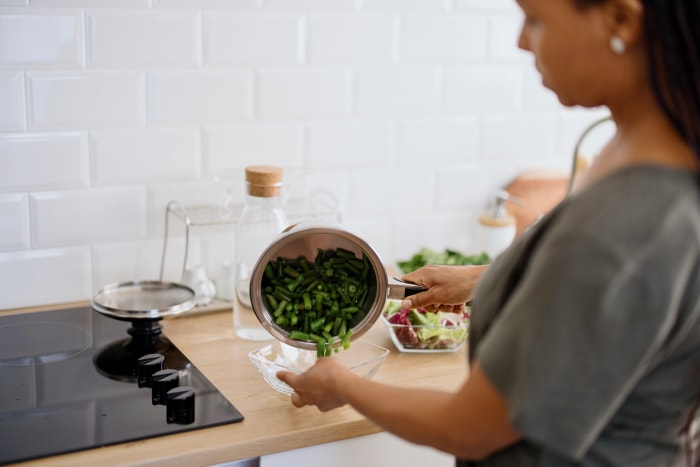 Femme africaine préparant des plats végétariens sains. Découpe de légumes en petits morceaux. Salade de légumes coupés en été