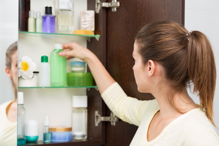 Belle fille choisissant des produits de beauté dans l'armoire de la salle de bain