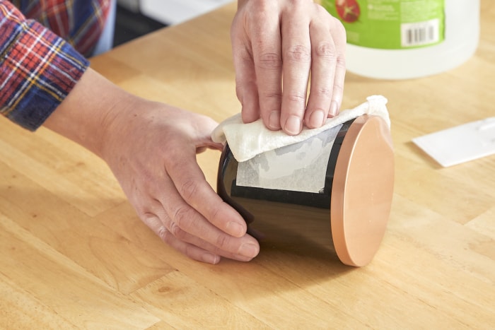 Une femme utilise du vinaigre pour retirer l’étiquette adhésive d’un pot.