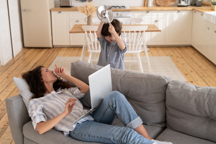 Une mère débordée demande à son fils de rester silencieux en surfant sur internet pour son travail. Parent et enfant en confinement covid