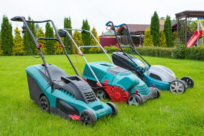 Lawn mowers are standing on the lawn in the garden backyard. A close-up of an electric lawn mower.