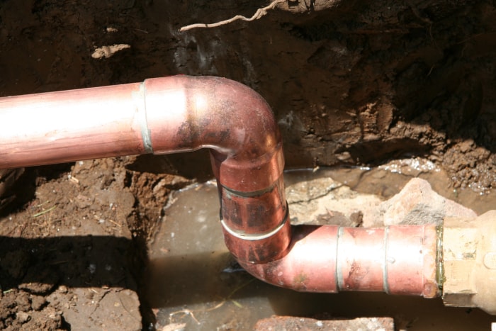 Un tuyau d'eau en cuivre fuit dans un sous-sol.