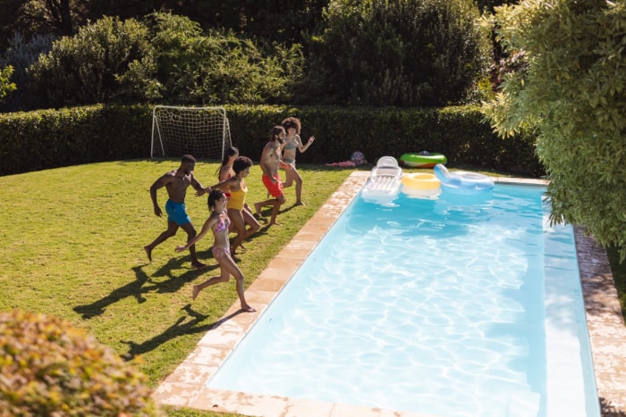 Un grand groupe d'amis sautant ensemble dans une piscine.