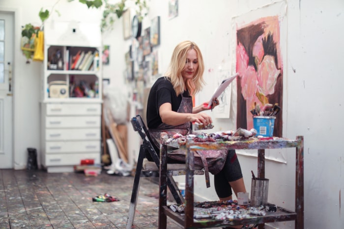 une femme mature, travaillant sur des peintures dans son atelier à domicile.