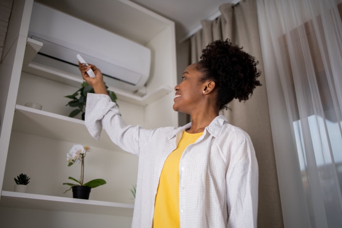 femme allumant un climatiseur mini-split avec une télécommande